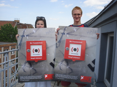 MUT-Mitarbeiter halten das neue Stern-Plakat für Zivilcourage